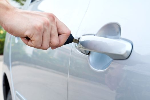 A hand opening a car door with a key