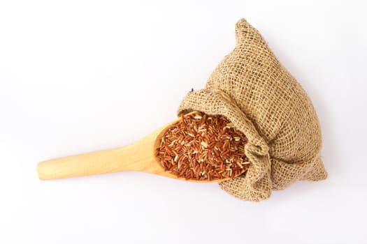 Wooden spoon with red rice in canvas sack.