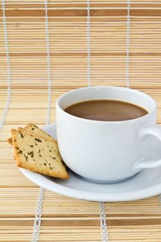 Coffee. White porcelain cup and three biscuit on a mat 