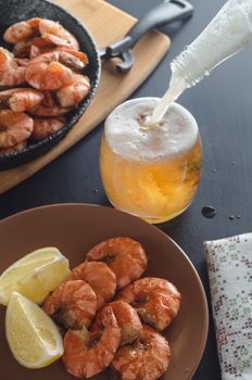 Fried shrimp on a platter, in the background filled with beer and a frying pan with shrimp.