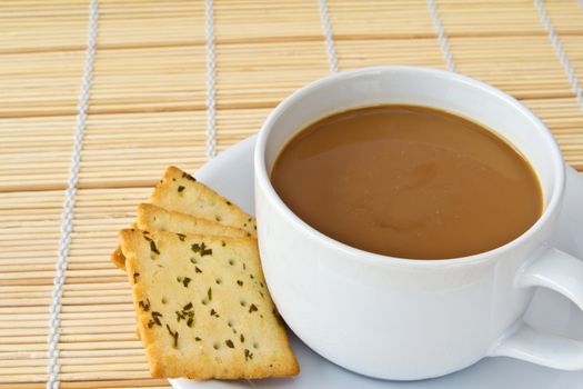 Coffee. White porcelain cup and three biscuit on a mat 