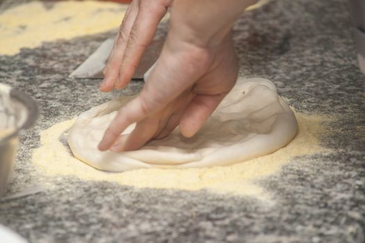 Man chef with raw pizza. Young male in uniform preparing pizza on table.