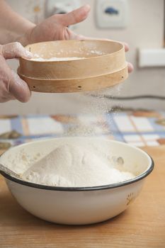 Women's hands preparing flour before baking pie.