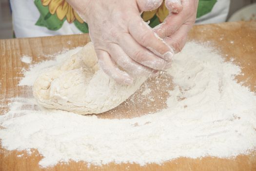 Women's hands preparing fresh yeast dough on wooden table