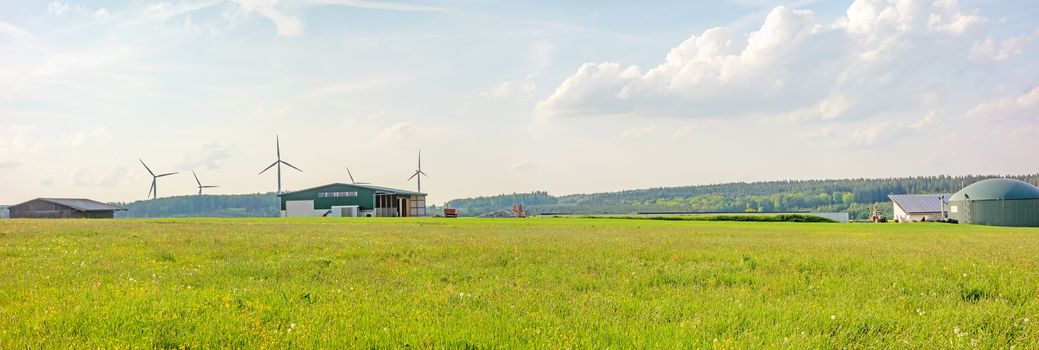 Farm with barn and biogas plant, green meadow in front