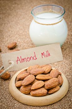 Almond and almond milk in glass with almond tag on wood background.