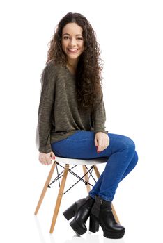 Beautiful woman sitting on a chair and smiling, isolated over white background 