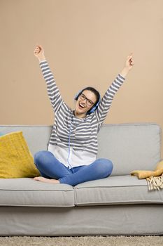 Beautiful woman at home sitting on the sofa and listen music