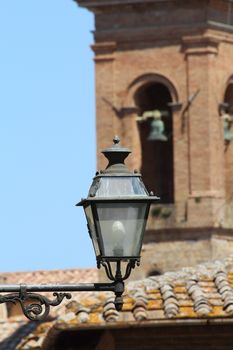 Medieval street lamp with church tower in the background