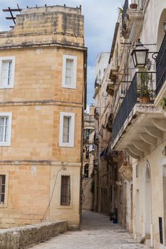 All the old stone buildings in the light orange color with small windows and balconies. Senglea, mediterranean island Malta.