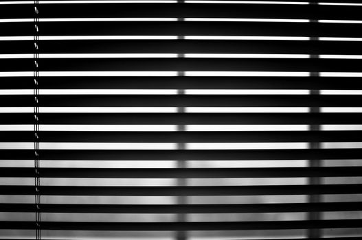 Closeup of semi open blinds in black and white.