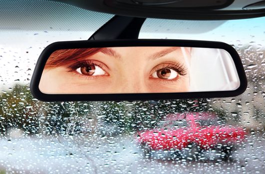 woman sits on driver's seat and Looks in the rear-view mirror