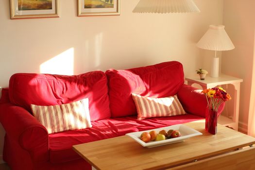Cosy red couch in summerhouse in the afternoon