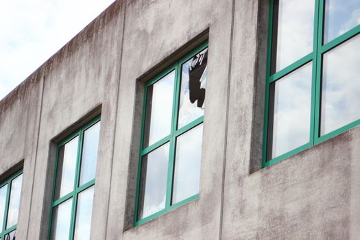 Broken glass in window with green frame at  factory