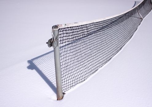 Tennis net at wintertime with snow and shadow
