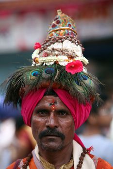 Pune, India - July 11, 2015: A portrait of a Vasudev, pilgrims who are devotees of Lord Vishnu and wear a conical hat with peacock feathers. Vasudev has been a traditional since many years in Maharashtra. THese pilgrims go around singing praises of Lord Vishnu.