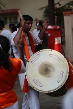 Pune, India - September 17, 2015: A hindu guy playing the traditional percussion instrument Dhol during a Ganesh festival procession
