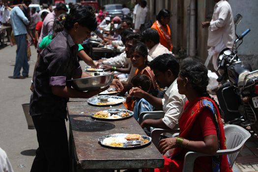 Pune, India - July 11, 2015: Indian pilgrims known as warkaris been served free meal on the side of the road during Wari festival in India.