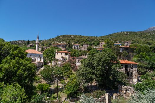 Landscape view of historical Doganbeyli village in Aydin, Turkey with historical small stone houses on bright blue sky background.