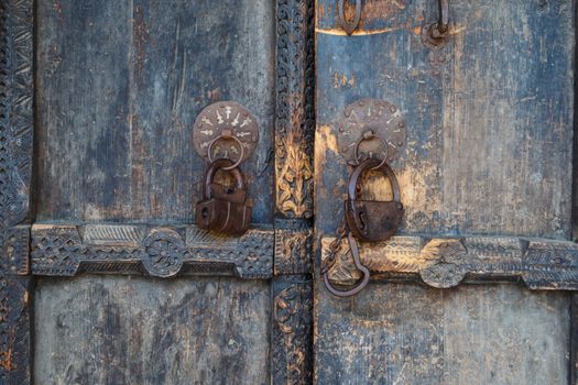 Close up front view of wooden old door, closed with chains and locked with padlock.