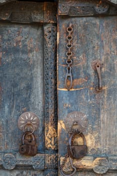 Close up front view of wooden old door, closed with chains and locked with padlock.