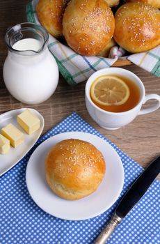 Bun with sesame seeds with slices of butter, milk, tea for breakfast