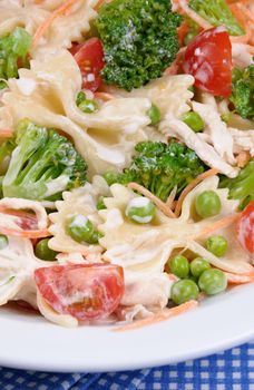 Salad of broccoli, peas, carrots, pasta, cherry tomatoes, slices of chicken in milk sauce