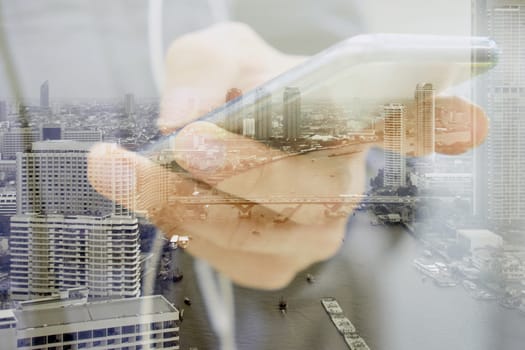 Double exposure image of businessman using smart phone with cityscape background, Business technology concept.