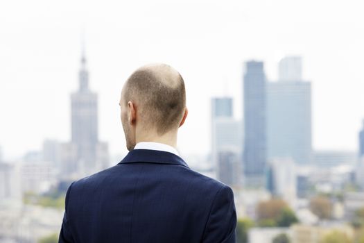 Businessman standing on the roof and looking at downtown