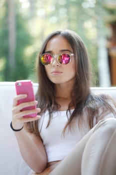 Beautiful young girl with smartphone sitting outdoors