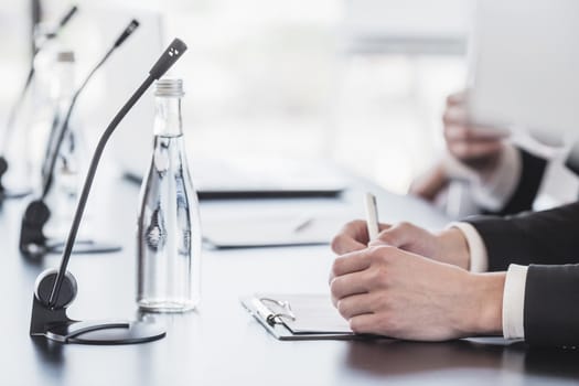 Microphones on table in conference room and business man hands 