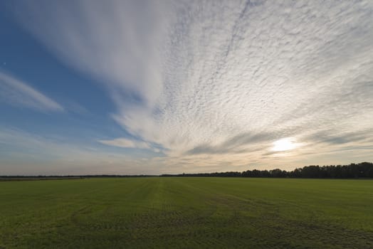 Vast mowed grass land with beautiful evening sky and clouds
