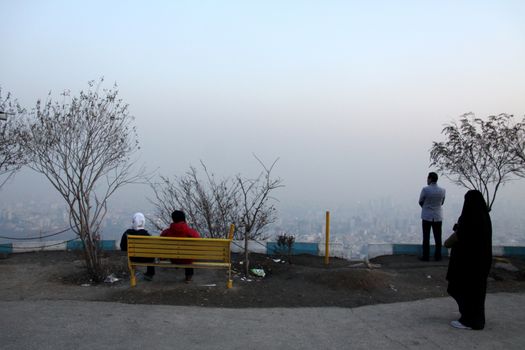IRAN, Tehran: People sit and look over the skyline of Tehran on December 29, 2015, as thick clouds of pollution hang over the city.The city of an estimated 14 million people was also forced to close schools last week due to the lingering pollution.