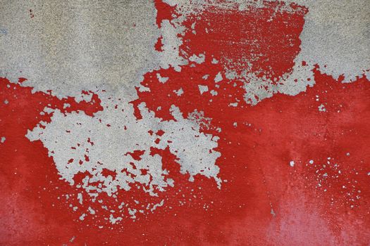 Flakes of old vintage grungy bright vivid red paint on grey concrete wall