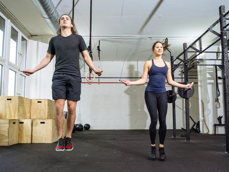 Photo of a fit young man and woman skipping rope at the gym.

