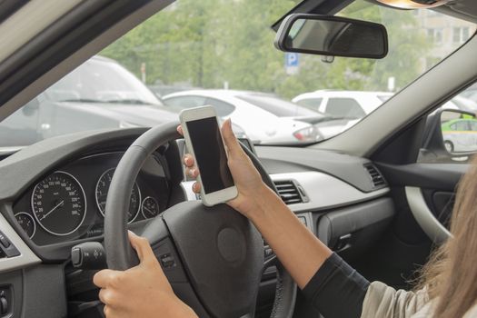 girl with a mobile phone behind the wheel in the saloon car