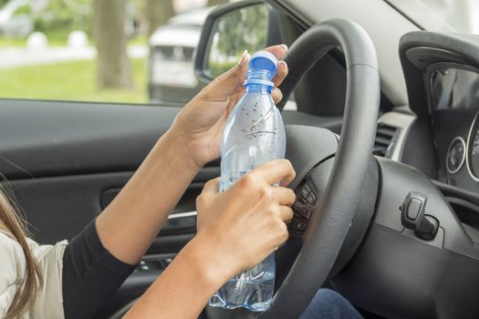 the girl in the cabin of the car holding a bottle of water