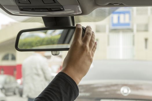 girl adjusts the rear view mirror in a car