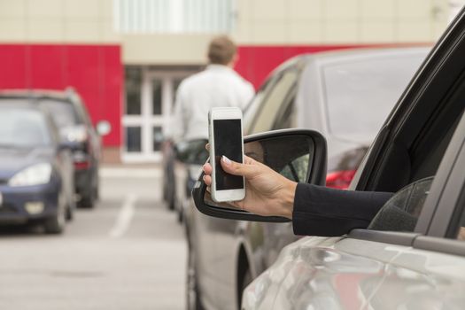 a girl takes pictures on a cell phone from the car window