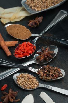 Spices and herbs on black wood background