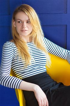 Happy cute woman sitting on the chair overblue background