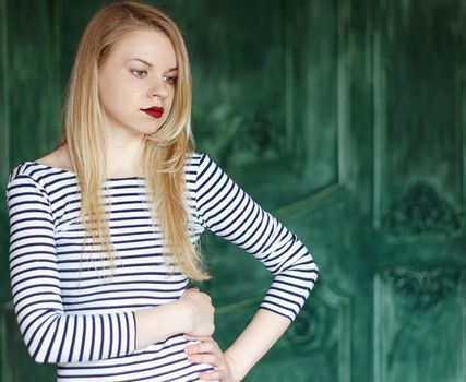 Blonde with red lips in a striped shirt on a green background a grunge wall