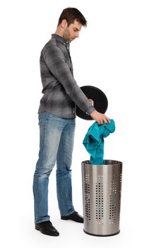 Young man putting a dirty towel in a laundry basket, isolated