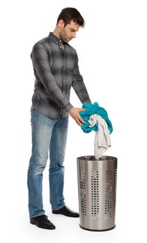 Young man putting a dirty towel in a laundry basket, isolated