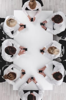 Business people sitting around the table with cell phones