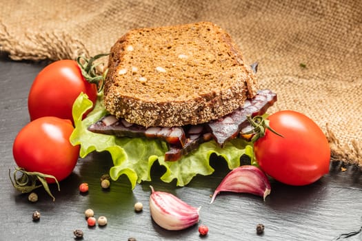sandwich with sausage and vegetable on a dark background