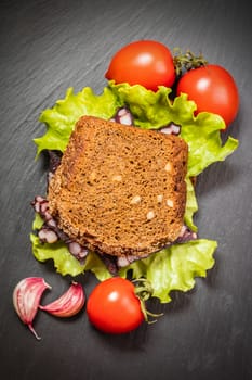 sandwich with sausage and vegetable on a dark background