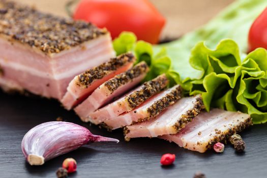 bacon in spices and vegetables on dark background