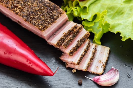 bacon in spices and vegetables on dark background