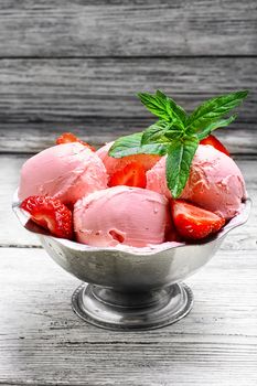 Ice cream with strawberries and leaves of mint in the iron bowl